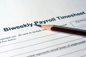 A close-up of a biweekly payroll timesheet with a sharpened pencil on top. The image conveys work-related focus and organization.