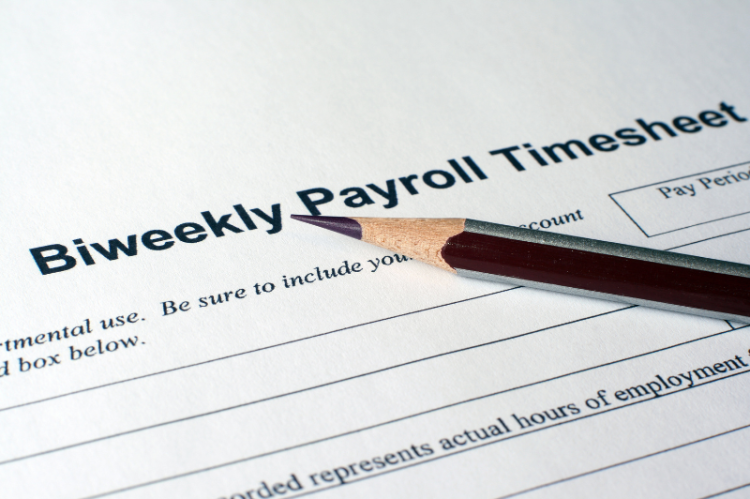 A close-up of a biweekly payroll timesheet with a sharpened pencil on top. The image conveys work-related focus and organization.